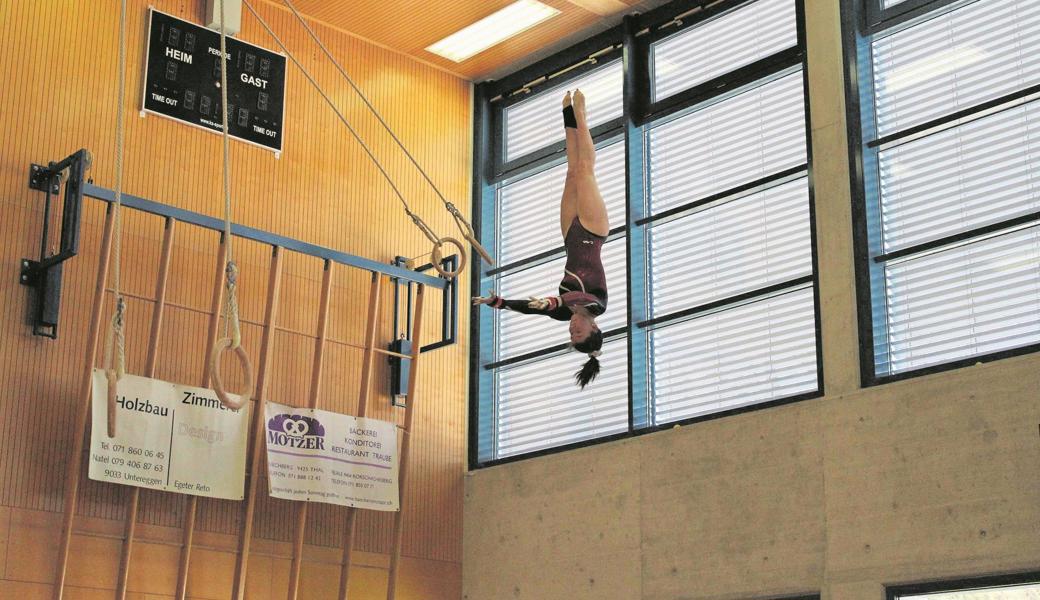 Nora van der Linden zeigt an den Schaukelringen einen Salto gestreckt.