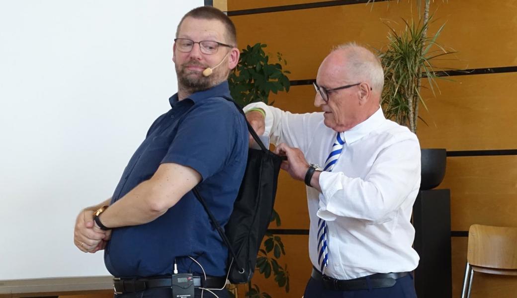 Präsident Armin Bartl (rechts) überreicht dem scheidenden Jugendpfarrer Jens Mayer einen Rucksack mit Inhalt.