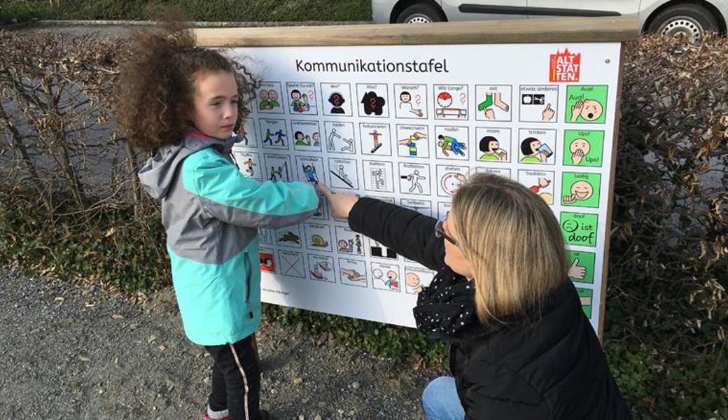 Andrina kann nicht sprechen. Mit der Kommunikationstafel auf dem Spielplatz Wiesental kann sie ihrer Mutter Katharina Dellai-Schöbi nun mitteilen, was sie spielen möchte.