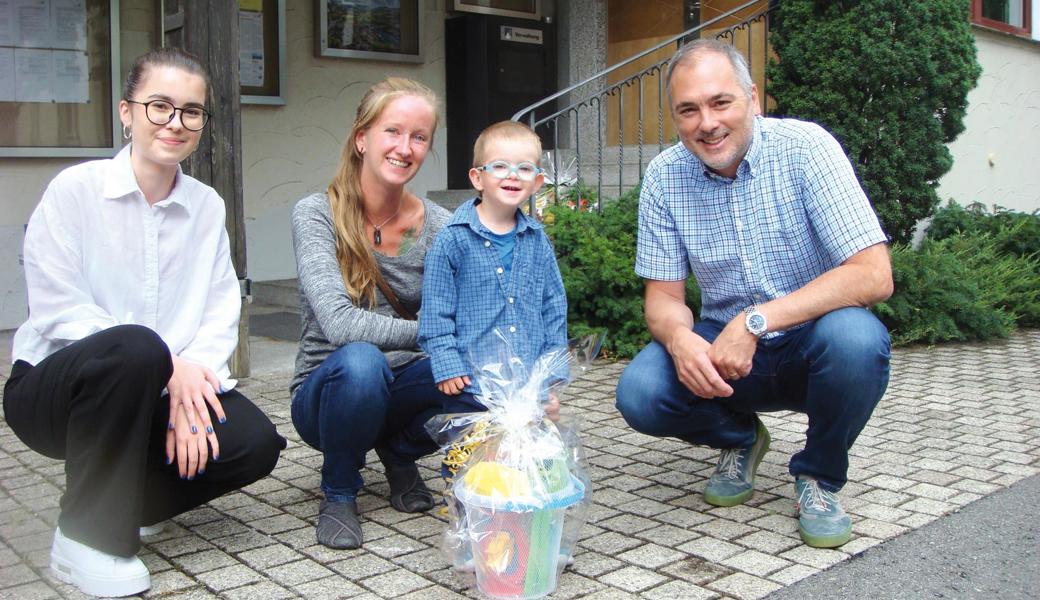 Mason und seine Mama Maria Wellinger freuen sich über das kleine Geschenk, das von Gemeindepräsident Christian Sepin (rechts) und Sara Skara (links) überreicht wurde. 