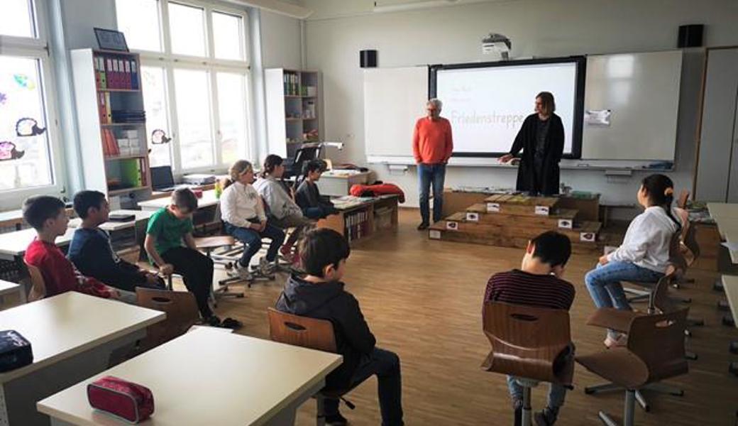 Die Schulsozialarbeiter Antonio Secco (links) und Alexandra Bösch (rechts) erklären den Kindern anhand aktueller Streitsituationen die Anwendung der Friedenstreppe.