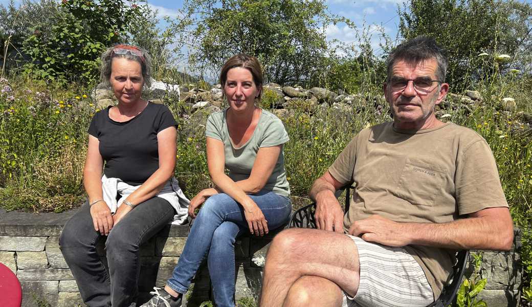 Geschäftsführerin Cora Barth (links) , Stellvertreterin Samsara Garcia-Reck und Naturgärtner Patrick Reck sitzen im naturnahen Garten vorden Büroräumlichkeiten der Wildblumen GmbH.