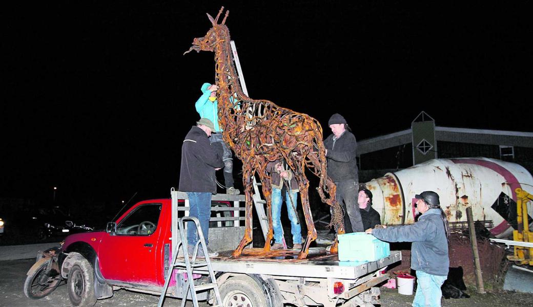 Silvan Köppel (3. von rechts) umhüllt gemeinsam mit seinen Helfern die Giraffe mit im Petrol eingeweichter Jutenschnur. Wer sehen möchte, wie die Giraffe brennt, scannt das Bild mit der App Xtend.   