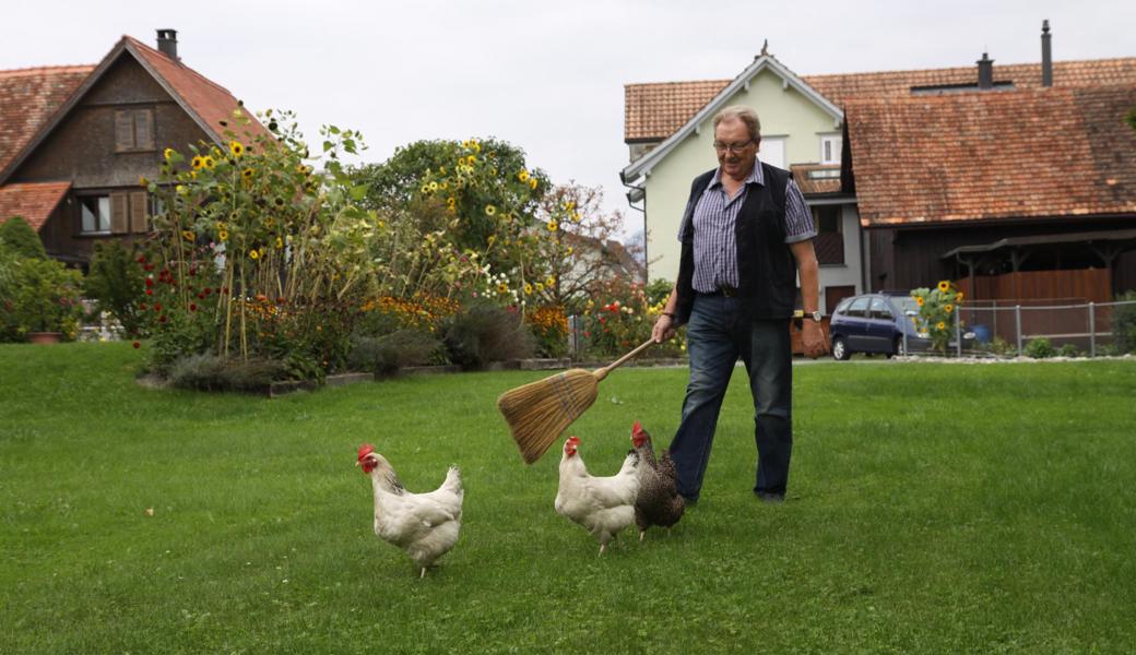 Kläus Sieber mit seinen drei Hühnern. Der Besen ist sein verlängerter Arm und Wegweiser. 