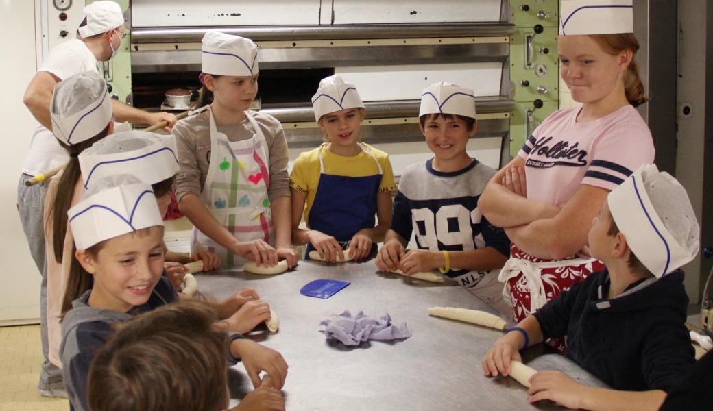 Die Kinder spornen sich gegenseitig an, die schönste Hefeschnecke zu formen. 