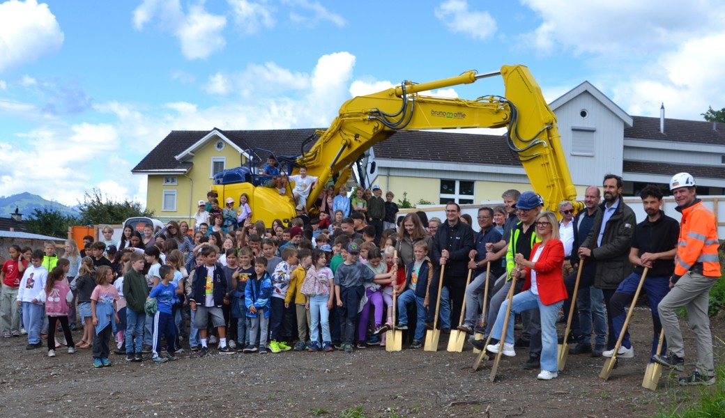 Ein Loch im Boden und ein Bagger auf der Wiese kündigen das entstehende neue Schulhaus an