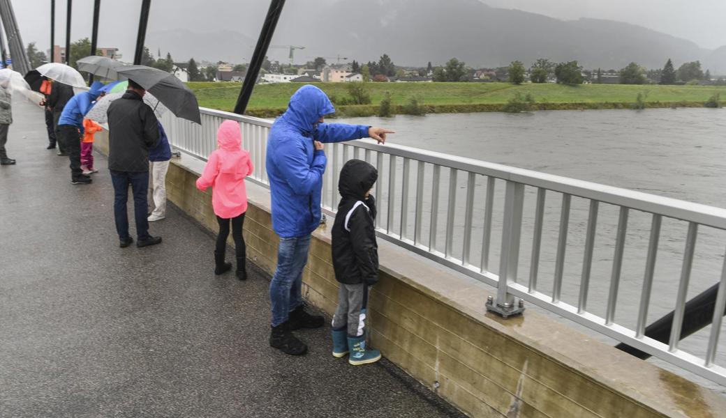 Leute blicken von der Diepoldsauer Rheinbrücke auf den Fluss.