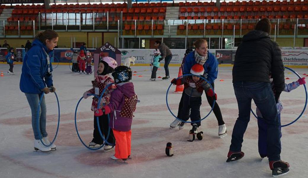 Kindern wird spielerisch das Eislaufen beigebracht. 