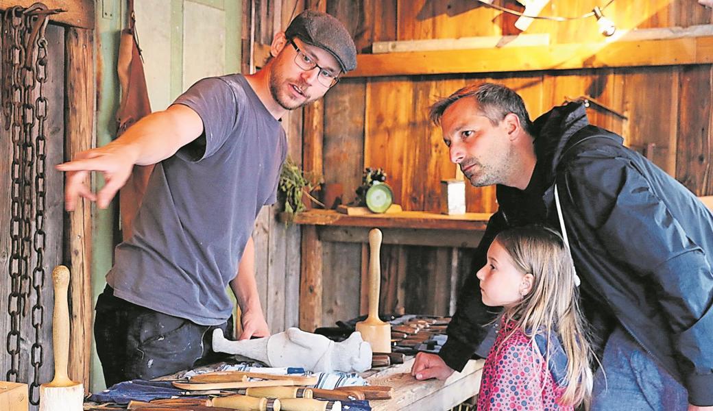 Holzbildhauer Kurt Müller erklärt interessierten Besuchern im Handwerkercontainer seine Arbeitsweise.