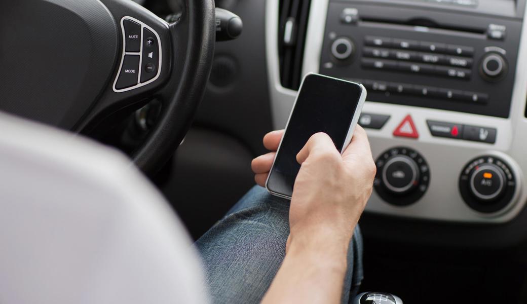 Nicht sehr klug: Während des Autofahrens Textnachrichten ins Handy eingeben.