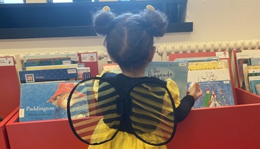 Ein Bienli stöbert in der Bibliothek bei den Kinderbüchern