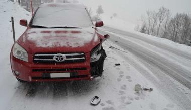 Zwei Autos stossen auf schneebedeckter Strasse zusammen